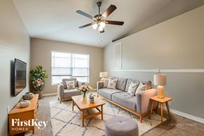 Deltona house for rent - A living room with a grey couch, a coffee table, a television, and a potted plant.
