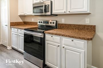 Jacksonville house for rent - a kitchen with white cabinets and granite counter tops and black appliances