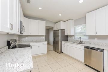 Groveland house for rent - a white kitchen with white cabinets and stainless steel appliances