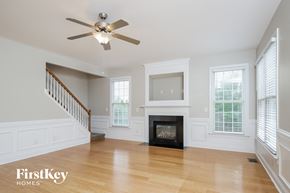 Winston Salem house for rent - an empty living room with a fireplace and a ceiling fan