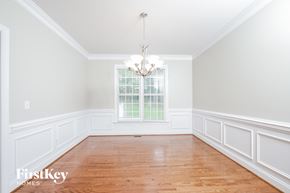 Winston Salem house for rent - an empty dining room with white wainscoting and a chandelier