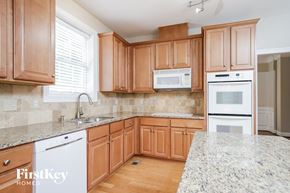 Winston Salem house for rent - a kitchen with wooden cabinets and granite counter tops and white appliances