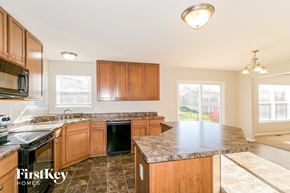 Saint Charles house for rent - a kitchen with wooden cabinets and granite counter tops and a black stove top oven