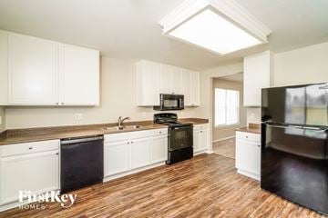 Converse house for rent - A kitchen with white cabinets and a black fridge.