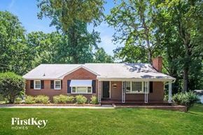Winston Salem house for rent - a brick house with a lawn and trees