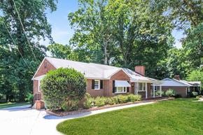 Winston Salem house for rent - the front of a brick house with a lawn and a driveway
