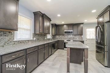 Winston Salem house for rent - a kitchen with dark cabinets and granite counter tops and stainless steel appliances