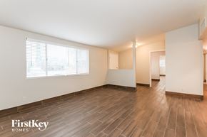 Tucson house for rent - A spacious room with wooden flooring and a large window.