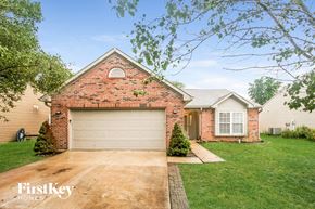 Franklin house for rent - A brick house with a garage door and a small tree in front of it.