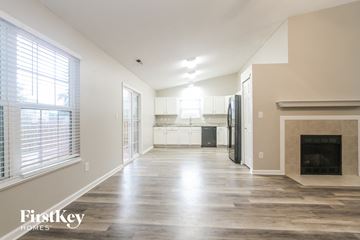 Franklin house for rent - A spacious living room with a fireplace and a kitchen in the background.