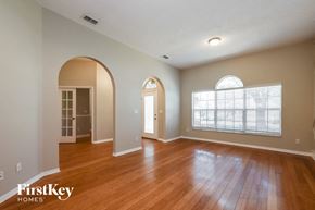Eustis house for rent - A spacious room with wooden floors and arched doorways.