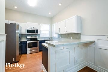 Eustis house for rent - A kitchen with white cabinets and a wooden floor.