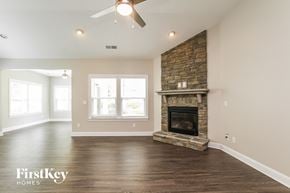 Mooresville house for rent - A spacious living room with a stone fireplace and a ceiling fan.