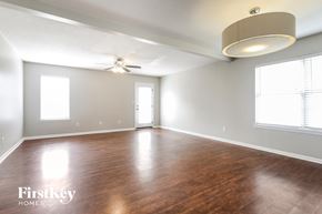 Greenwood house for rent - A spacious room with wooden floors and a ceiling fan.