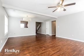 Greenwood house for rent - A spacious room with wooden floors and a ceiling fan.