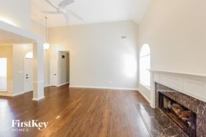 Helena house for rent - A large empty room with a fireplace and wooden floors.