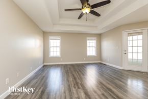 Clarksville house for rent - A spacious room with a ceiling fan and wooden flooring.