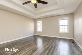 Clarksville house for rent - A spacious room with wooden floors and a ceiling fan.