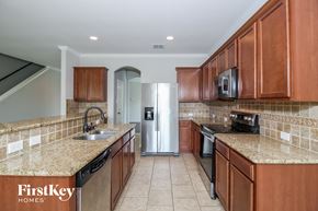 Burleson house for rent - a kitchen with wooden cabinets and granite counter tops and a refrigerator