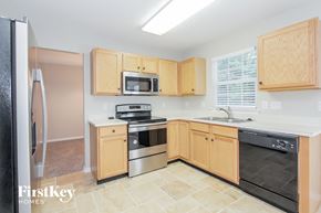 Charlotte house for rent - a kitchen with wooden cabinets and black appliances and a sink