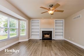 Wentzville house for rent - A spacious room with a fireplace and a ceiling fan.