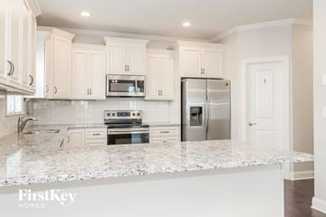 Lexington house for rent - a kitchen with white cabinets and a marble counter top