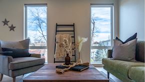 Denver apartment for rent - A living room with a grey couch, a wooden table, and a ladder leaning against the wall.