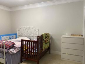 Vancouver apartment for rent - A white bed with a blue headboard and a white dresser with a wooden top.