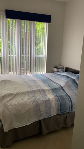 Vancouver apartment for rent - A bed with a white and blue striped comforter.