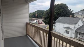 Woonsocket apartment for rent - A view from a balcony looking out at a street with houses and trees.