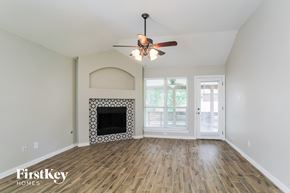Conroe house for rent - a living room with a fireplace and a ceiling fan