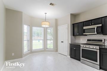 Conroe house for rent - a kitchen with black cabinets and a stove and a window