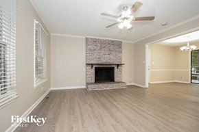 Trinity house for rent - A spacious room with a fireplace and a ceiling fan.