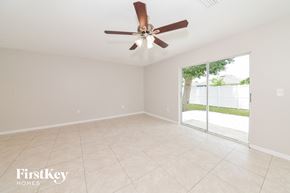 Sarasota house for rent - A room with a ceiling fan and sliding glass doors.