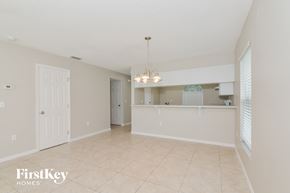 Sarasota house for rent - A spacious room with a chandelier and a kitchen area in the background.