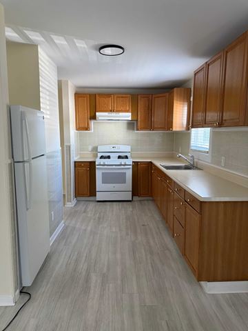 New Haven apartment for rent - A kitchen with wooden cabinets and a white stove top oven.