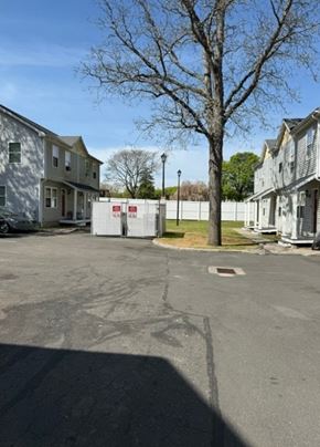 New Haven apartment for rent - A parking lot with a white fence and a tree in the background.