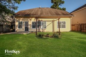 Humble house for rent - the backyard of a yellow house with a covered porch and grass