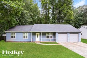 Kennesaw house for rent - A blue house with a garage is surrounded by green trees.