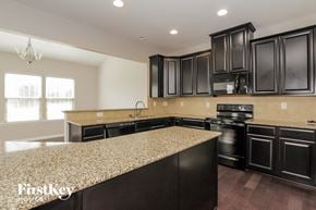 Mooresville house for rent - a kitchen with black cabinets and a granite counter top