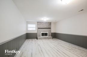 Manchester house for rent - A spacious room with wooden flooring and a brick fireplace.