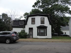 New Glasgow apartment for rent - A white house with a black door and windows is surrounded by trees.