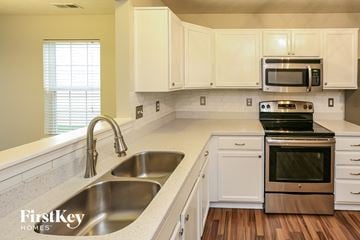 Noblesville house for rent - a kitchen with white cabinets and stainless steel appliances