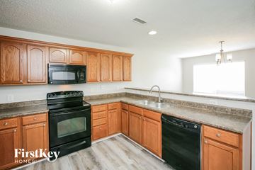 Noblesville house for rent - a kitchen with wooden cabinets and black appliances