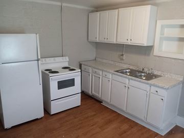Stantonsburg apartment for rent - A white kitchen with a refrigerator, oven, and sink.