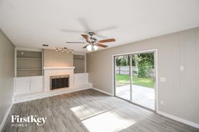 Orange Park house for rent - A spacious living room with a fireplace and sliding glass doors.