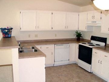 Neenah apartment for rent - a kitchen with white cabinets and a stove and a sink