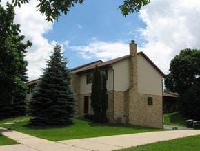 West Bend apartment for rent - a house with a sidewalk and two pine trees