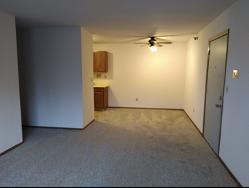 West Bend apartment for rent - an empty living room with a ceiling fan and a door to a kitchen