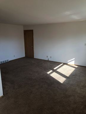 Menomonee Falls apartment for rent - an empty living room with white walls and a door